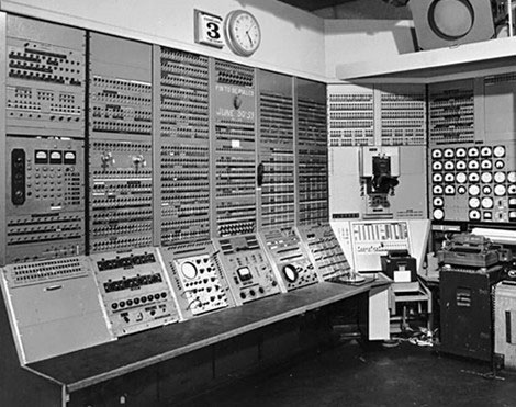 Early computer that takes up an entire room and looks very complex to operate
